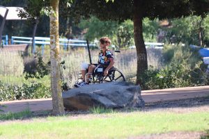 ילד מתנייד בכסא גלגלים, מחייך בשבילי הכפר